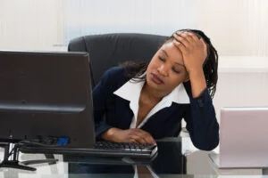 A businesswoman looking stressed at her desk